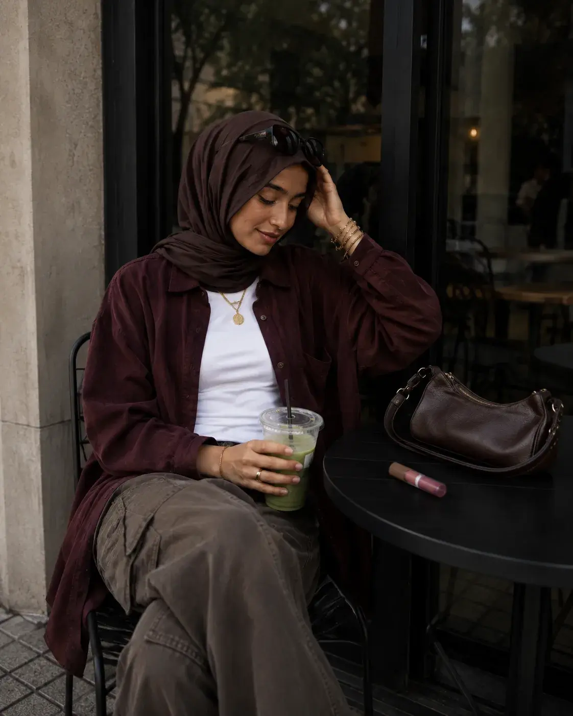 Shopper in a layered shirt and hijab at a cafe table
